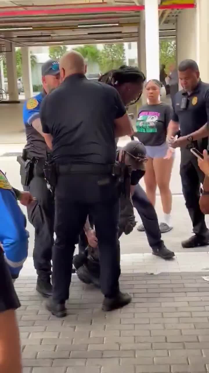 Cameraman ietwat afgeleid tijdens het filmen van een arrestatie