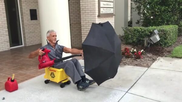 Conciërge vermaakt zich prrrima met een bladblazer en een paraplu