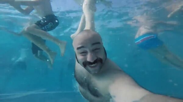 Vader met een blije kale klets neemt een onderwater selfie