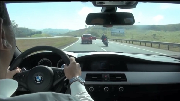 BMW M5 en motorrijder dagen elkaar uit en zigzaggen door het verkeer