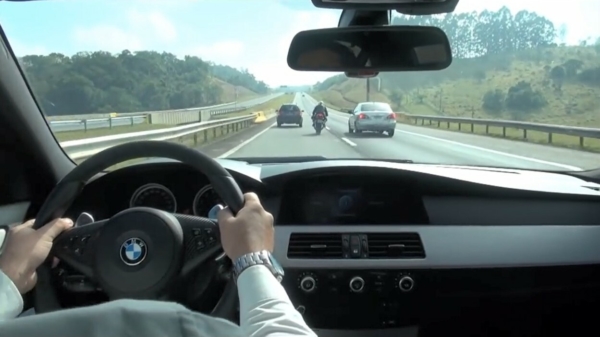 BMW M5 en motorrijder dagen elkaar uit en zigzaggen door het verkeer