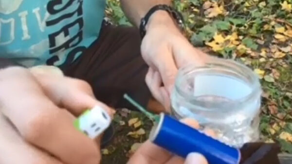 Buurman en Buurman stoppen een vuurwerkje in een glazen pot