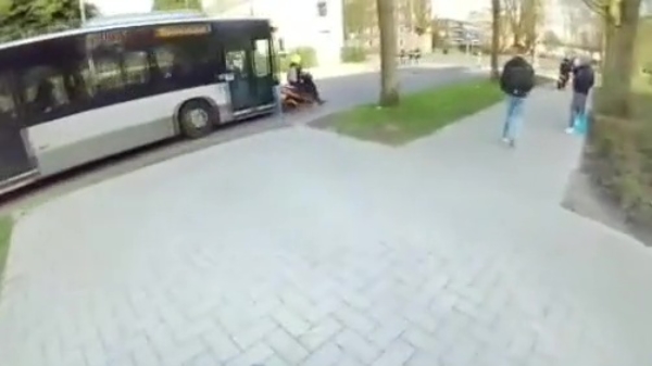 Scooterbinkie ziet aankomende bus niet en klapt onderuit