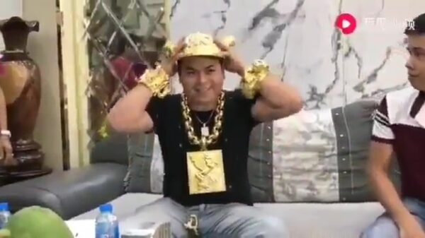 Met goud behangen Aziaat koopt ook nog even een gouden petje