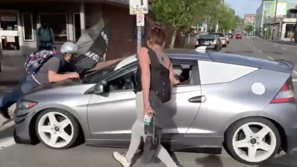 Kruispunt geblokkeerd door demonstranten, automobilist geeft gas