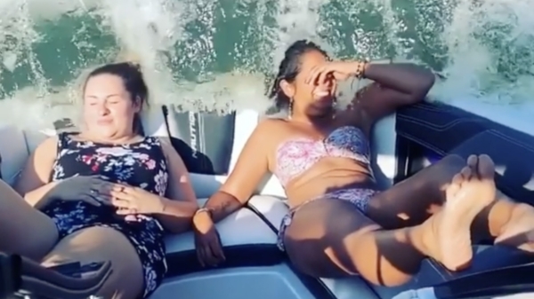 Zonnende dames op speedboot worden op lading water getrakteerd