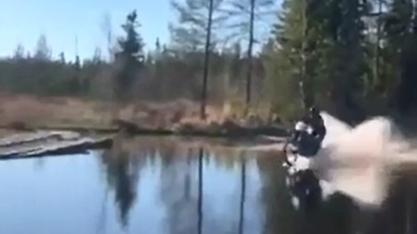 Stuntbink jankt met zijn crossmotor over het water