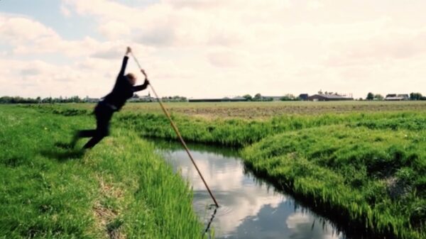 Fierljepper geeft een demonstratie hoe je over een sloot springt