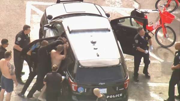 Politieagenten worstelen om verdachte in een auto te krijgen