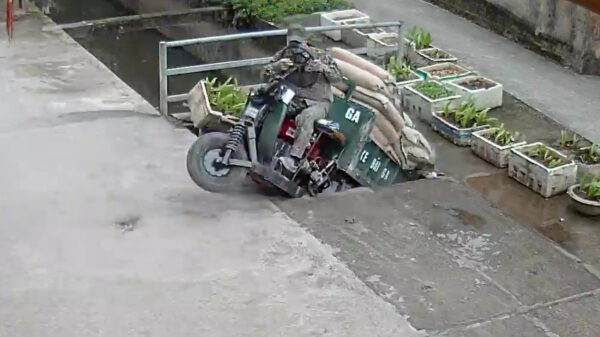 Vietnamees zakt met te zwaar beladen wagentje door betonnen stoep