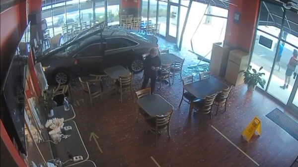 Bejaarde vrouw jankt met haar rijtuig vol door het raam van een restaurant