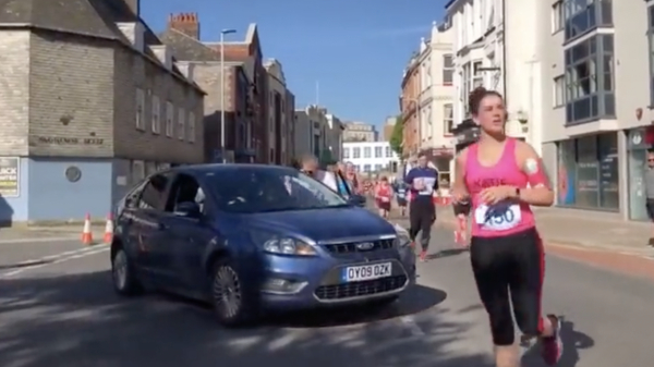 Seniel vrouwtje ramt met haar auto dwars door een marathon