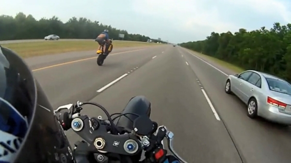 Stuntpiloot in t-shirt en korte broek doet een supersnelle wheelie op de snelweg