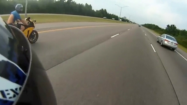 Stuntpiloot in t-shirt en korte broek doet een supersnelle wheelie op de snelweg