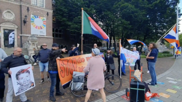 Oudere dame rijdt met fiets in op demonstratie van nationalistische Voorpost