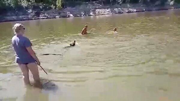 Russische vrouw laat haar huisdier lekker tussen de strandgangers spetteren