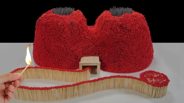Creatieve pyromaan bouwt een tweekoppige vulkaan van een hoop lucifers