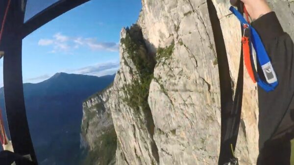 Basejumper kruipt door het oog van de naald als hij tegen berg klettert