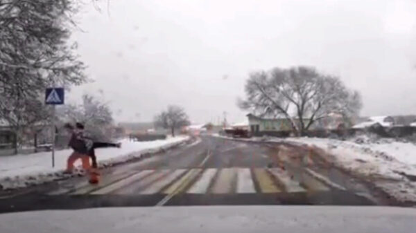 Held trekt op het zebrapad kind voor aanstormende auto vandaan