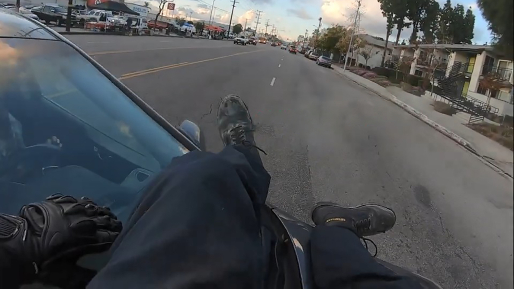 Motorrijder klapt tegen auto en landt met een salto netjes op de motorkap