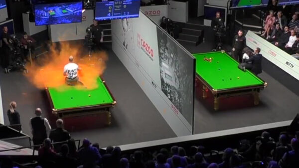 Klimaatgekkie klimt tijdens WK snooker op snookertafel en strooit met oranje poeder