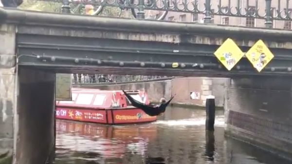Klimaatactivisten blokkeren gracht in Amsterdam door aan brug te hangen: wait for it