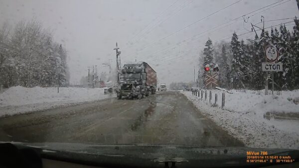 Gestrande vrachtwagen wordt door trein van het spoor af geholpen