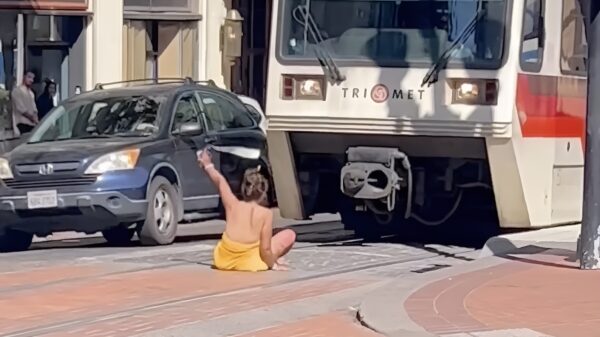 Een complete tram in Portland moet wachten op een wapperende vrouw