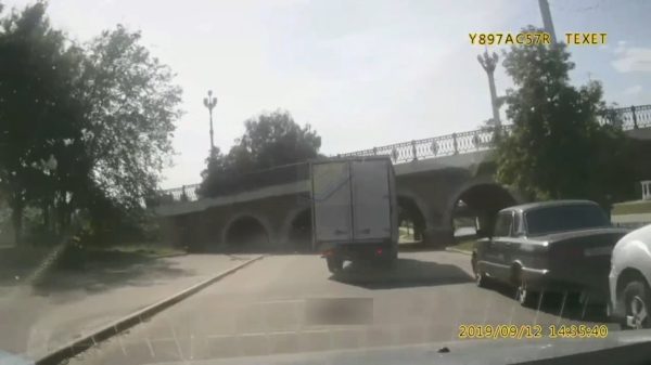 Vierkante vrachtwagenchauffeur probeert onder een ronde, lage brug door te rijden