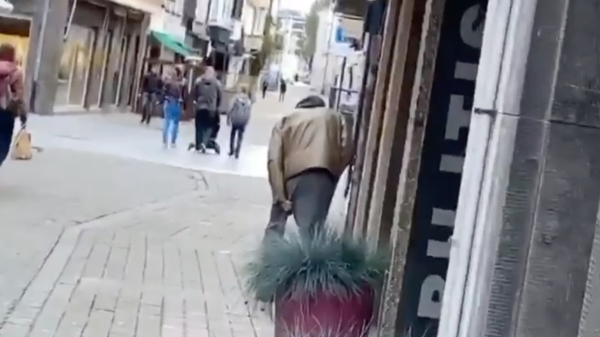 Belgische straatkakker schudt  in een winkelstraat wat verse vlaaien uit zijn broekspijp
