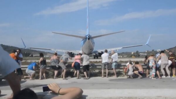 Toeristen laten zich vrijwillig zandstralen achter een Boeing op het Griekse eiland Skiathos