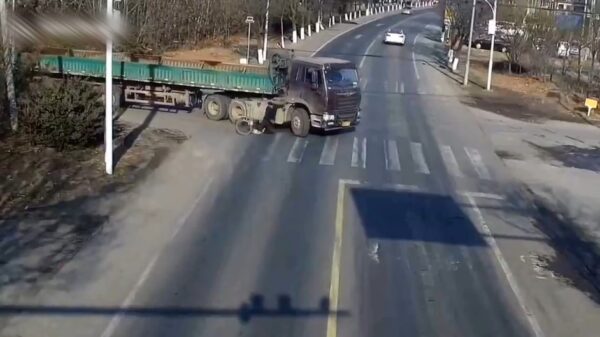 Chinese fietser mag van geluk spreken als hij onder een vrachtwagen belandt