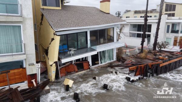 Golven slaan door kapotte zeewering tot tegen huizen in Long Beach