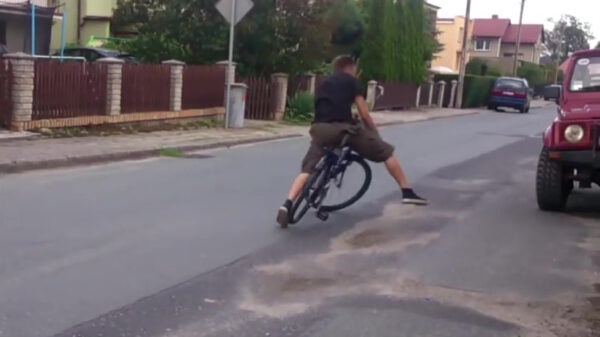 Enthousiaste fietser drift zijn stalen ros zo tegen een stilstaande Jeep