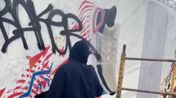 Graffiti-eikeltje zet zijn tag bovenop een stukje street-art van Adidas