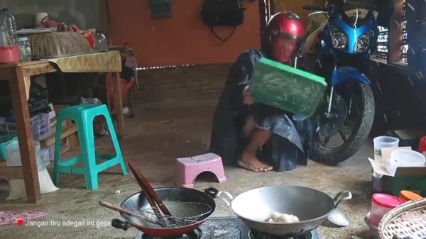 Aziaat draagt helm en regenpak tijdens koken explosieve maaltijd