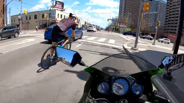 Motorrijder wordt aangetikt door plotseling afslaande hipster op wielrenfiets