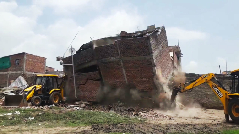 Indiase bulldozerbink staat iets te dicht bij gebouw dat gesloopt wordt