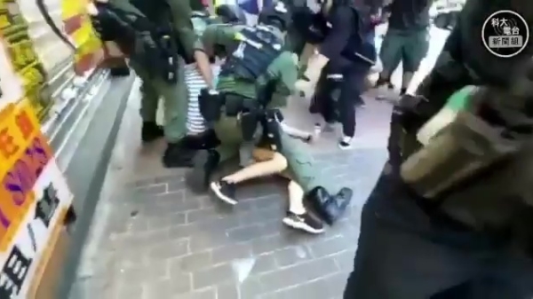 Jong meisje wordt hardhandig door de politie naar de grond gewerkt in Hong Kong