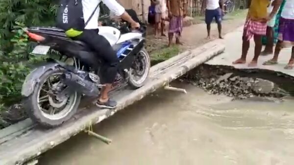 Koekenbakker probeert zijn motor stapvoets over bruggetje te rijden